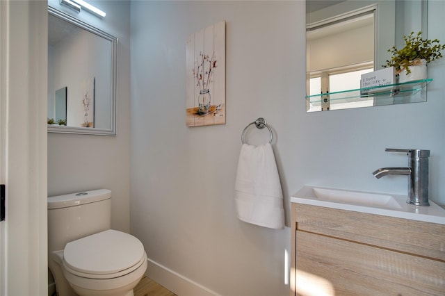 bathroom with toilet, baseboards, and vanity