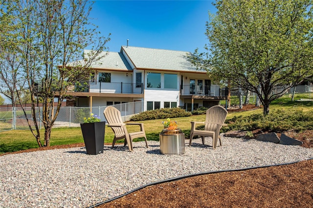 rear view of property featuring a yard, fence, and a balcony