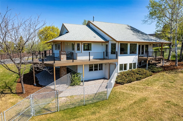 rear view of house with a yard, a deck, a fenced backyard, and a gate
