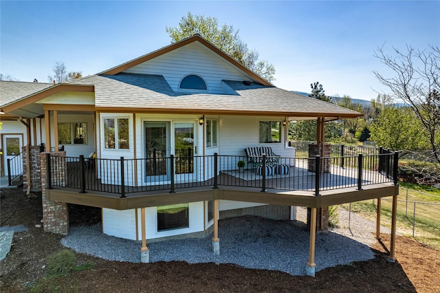 rear view of house featuring a shingled roof and a wooden deck