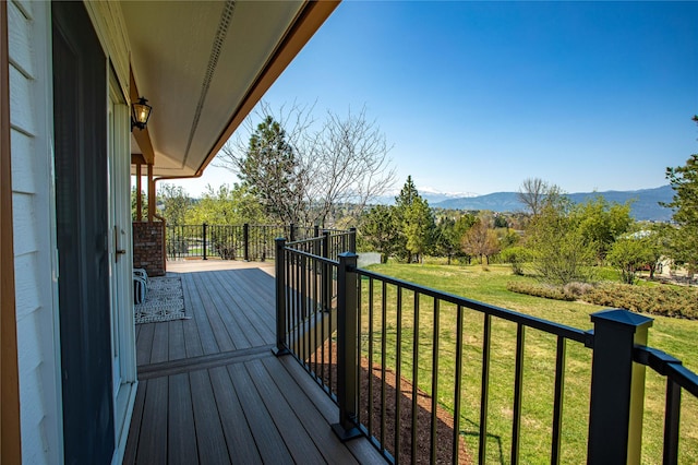 wooden terrace featuring a lawn and a mountain view