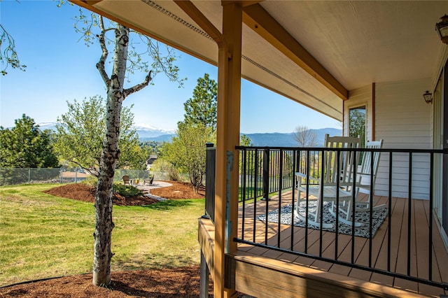 exterior space featuring fence, a mountain view, and a lawn