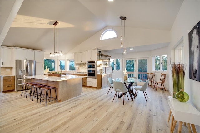 kitchen featuring stainless steel appliances, open shelves, high vaulted ceiling, light wood-style flooring, and white cabinetry