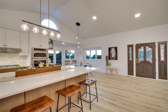 kitchen featuring light wood finished floors, appliances with stainless steel finishes, pendant lighting, and a breakfast bar
