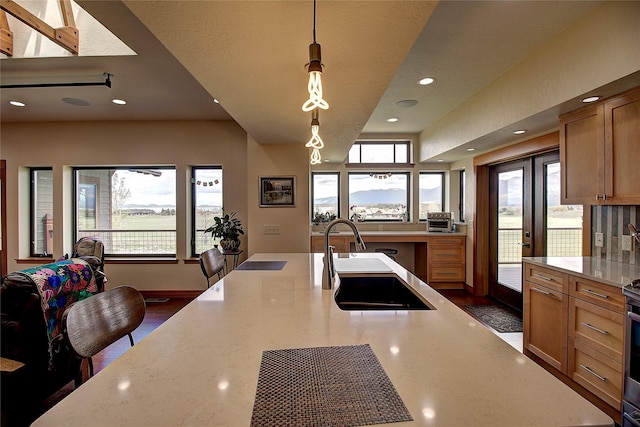 kitchen featuring recessed lighting, baseboards, light stone counters, hanging light fixtures, and a sink