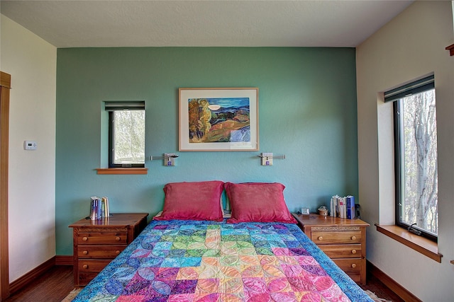 bedroom featuring baseboards, multiple windows, and wood finished floors