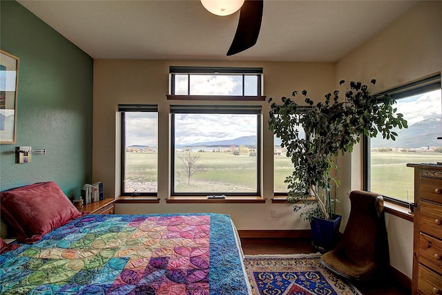 bedroom featuring baseboards, a ceiling fan, multiple windows, and wood finished floors