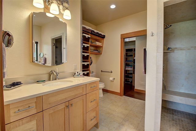 bathroom featuring toilet, vanity, recessed lighting, a walk in closet, and tiled shower