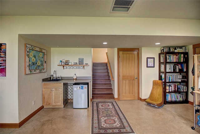interior space with wet bar, visible vents, baseboards, and a sink