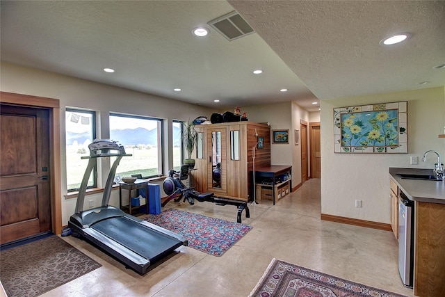 workout room featuring a textured ceiling, recessed lighting, visible vents, and a sink