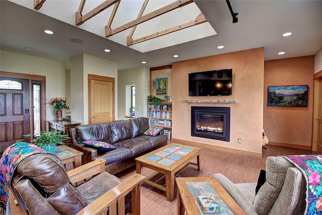 living area with light wood-type flooring, baseboards, a glass covered fireplace, and recessed lighting