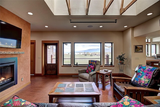 living room featuring baseboards, a high end fireplace, recessed lighting, and wood finished floors
