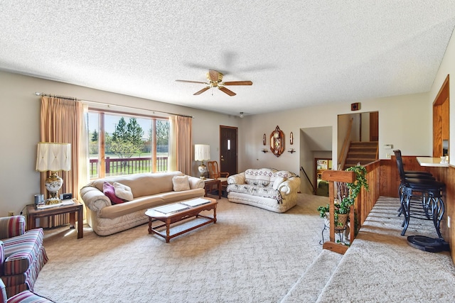 carpeted living area featuring a textured ceiling, stairs, and a ceiling fan