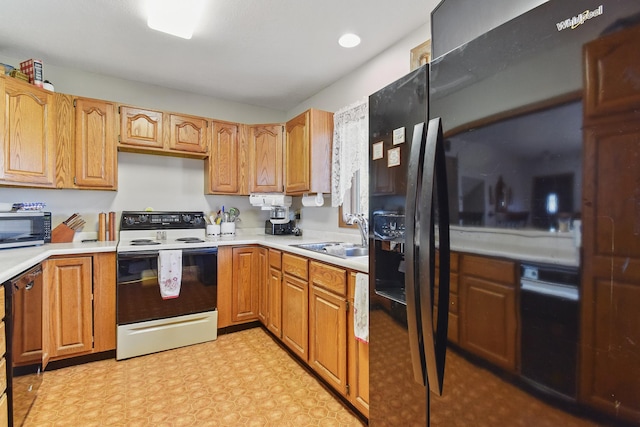 kitchen with a sink, stainless steel microwave, light countertops, and electric stove