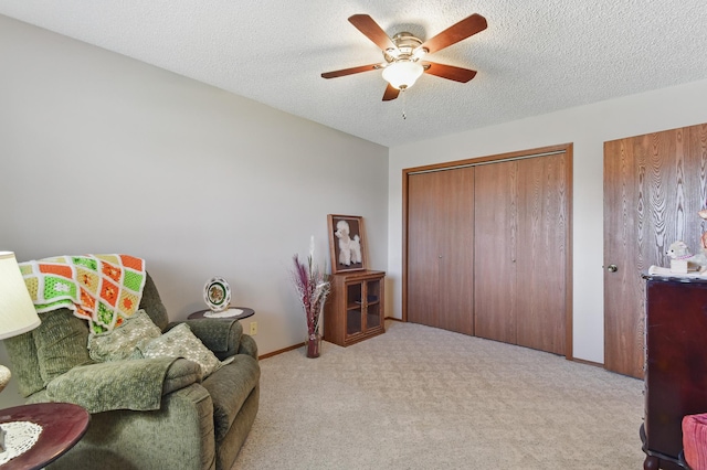 sitting room featuring ceiling fan, a textured ceiling, carpet flooring, and baseboards