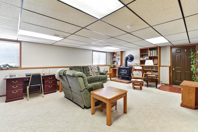 living room with a wood stove, carpet flooring, visible vents, and a drop ceiling