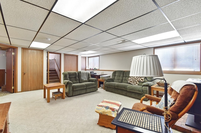 carpeted living area with a paneled ceiling and stairway