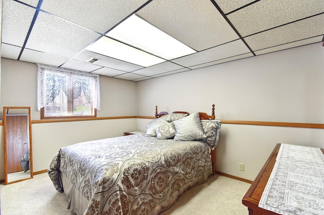 carpeted bedroom with a paneled ceiling, baseboards, and visible vents