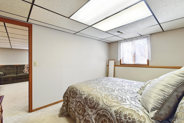 carpeted bedroom with a paneled ceiling, baseboards, and visible vents