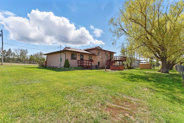 exterior space with a storage unit, fence, an outbuilding, and a deck