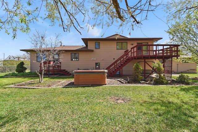 back of property with a yard, a deck, stairway, and a hot tub