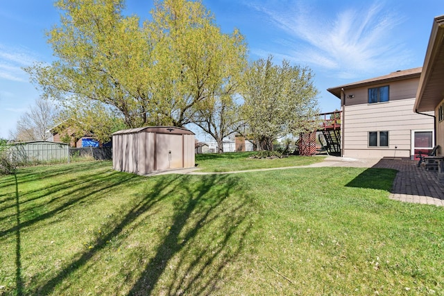 view of yard featuring fence, a patio area, stairs, an outdoor structure, and a shed