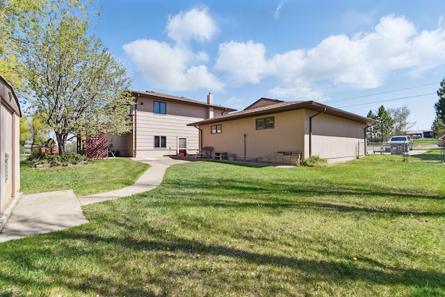 rear view of property with a lawn and fence