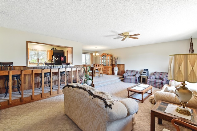 living room with a textured ceiling, carpet floors, and ceiling fan with notable chandelier