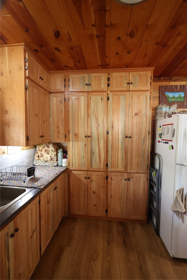 kitchen featuring freestanding refrigerator, wooden ceiling, a sink, and hardwood / wood-style flooring