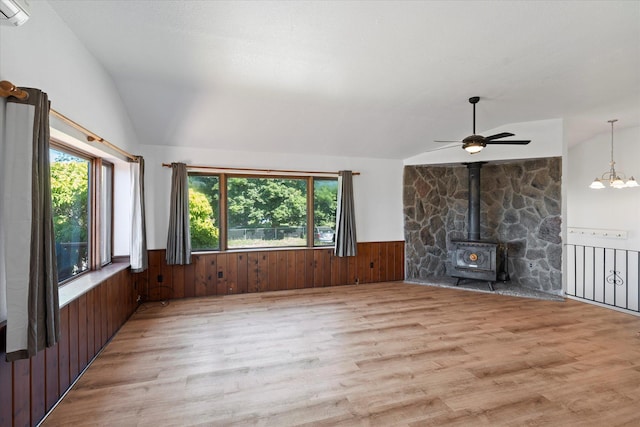 1108 9th St E, Polson, MT 59860 - unfurnished living room with lofted ceiling, light wood-type flooring, wainscoting, a wood stove, and wood walls