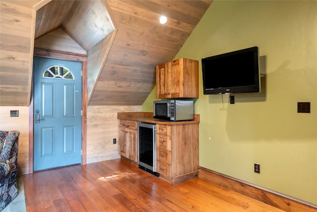 144 S Shore Pl, Seeley Lake, MT 59868 - kitchen featuring beverage cooler, stainless steel microwave, vaulted ceiling, hardwood / wood-style floors, and brown cabinets