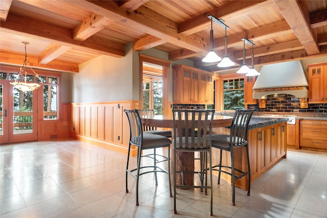 144 S Shore Pl, Seeley Lake, MT 59868 - kitchen with custom range hood, a wooden ceiling with exposed beams, a chandelier, wainscoting, and light tile patterned floors