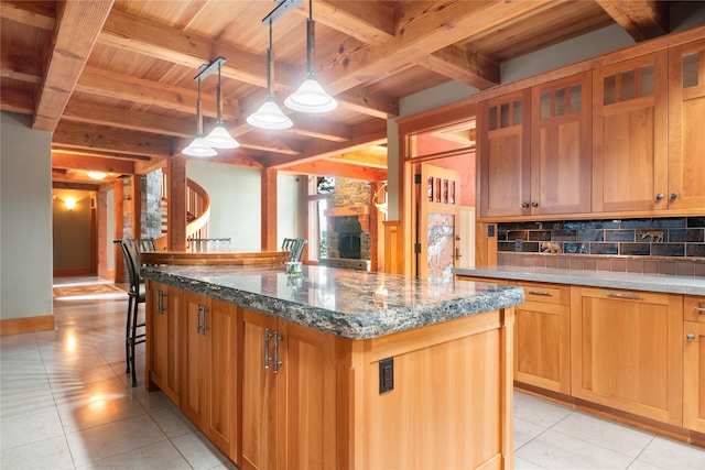 144 S Shore Pl, Seeley Lake, MT 59868 - kitchen featuring a wood ceiling with exposed beams, decorative backsplash, a center island, light tile patterned floors, and dark stone countertops