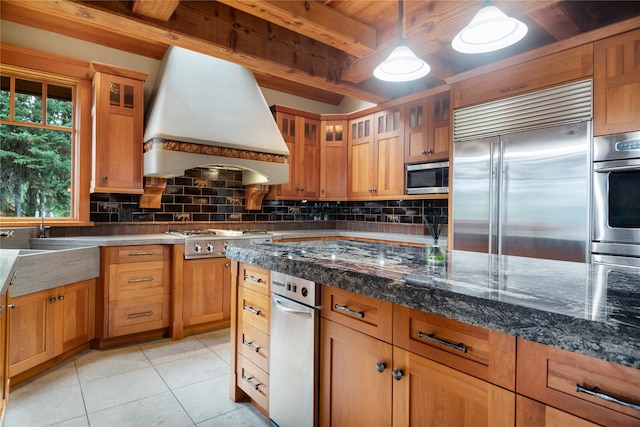 144 S Shore Pl, Seeley Lake, MT 59868 - kitchen with stainless steel appliances, custom exhaust hood, tasteful backsplash, light tile patterned floors, and glass insert cabinets