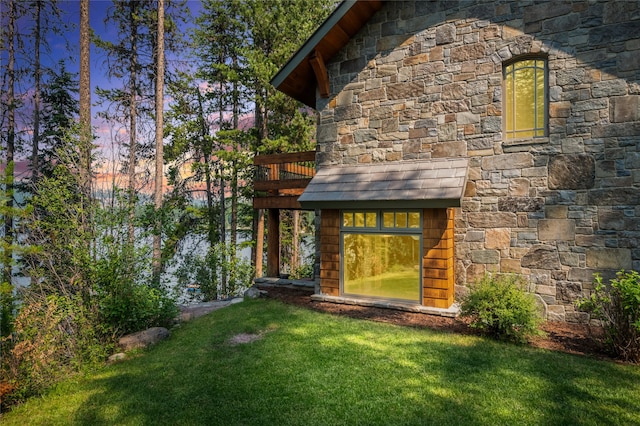 144 S Shore Pl, Seeley Lake, MT 59868 - view of front of property featuring stone siding, a lawn, and a deck