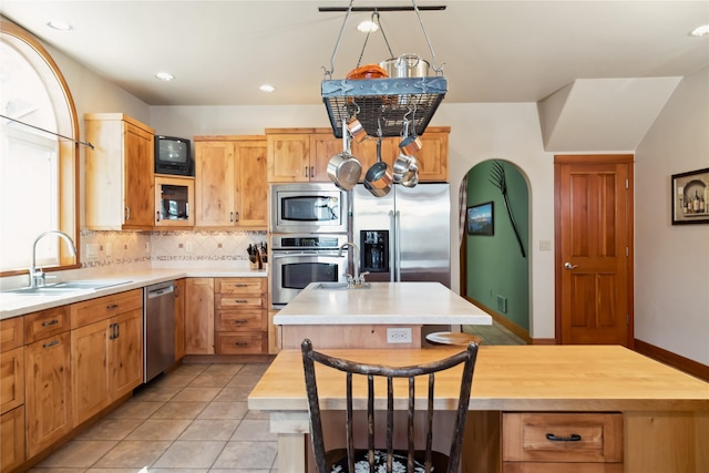 42746 Knuppel Ln, Big Arm, MT 59910 - kitchen with stainless steel appliances, a sink, an island with sink, light tile patterned floors, and tasteful backsplash