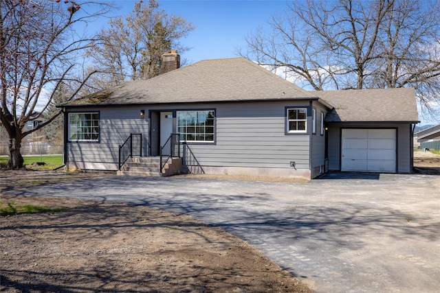 view of front of property with an attached garage, driveway, and a chimney