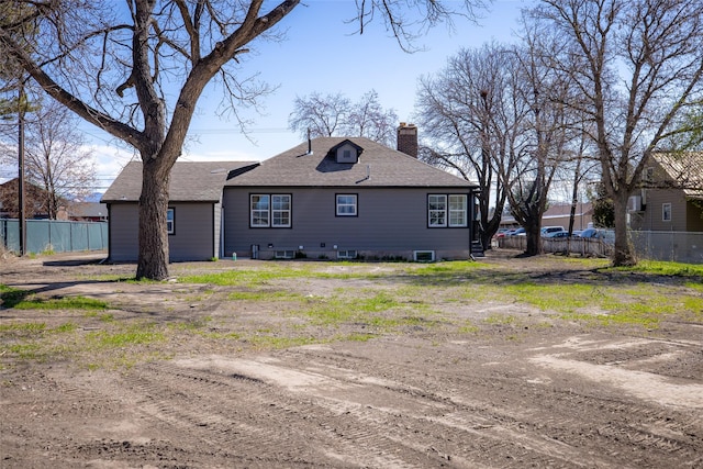 exterior space with a shingled roof, fence, and a chimney