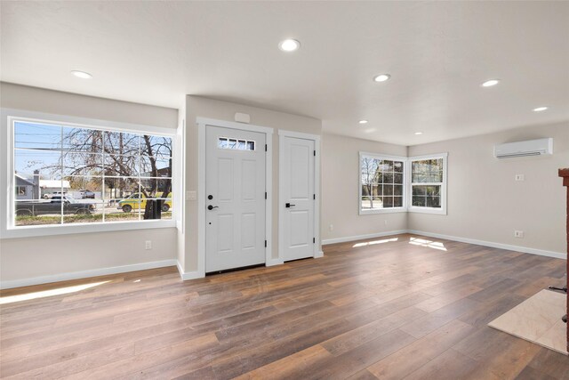entrance foyer featuring wood-type flooring, baseboards, a wall mounted AC, and recessed lighting