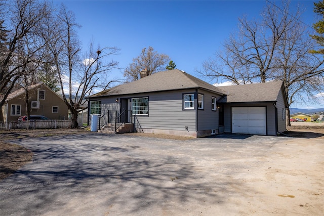 view of front facade with fence, a chimney, roof with shingles, driveway, and a detached garage