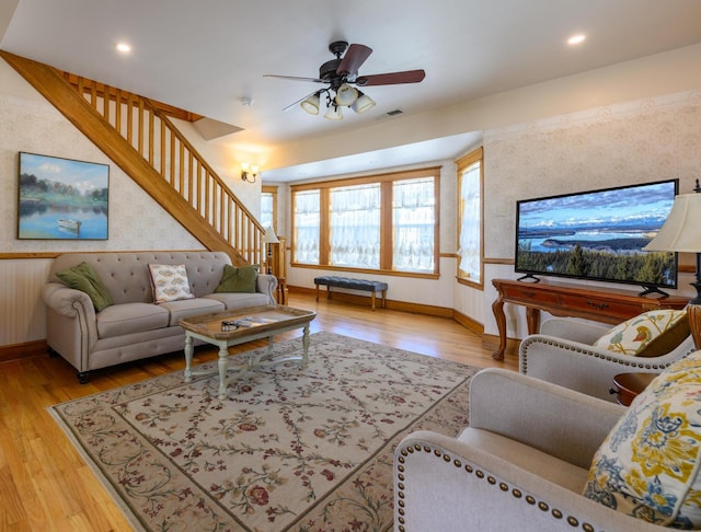 living room with baseboards, stairway, light wood-style flooring, and a ceiling fan