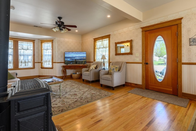 foyer entrance with light wood finished floors, wallpapered walls, visible vents, and a ceiling fan
