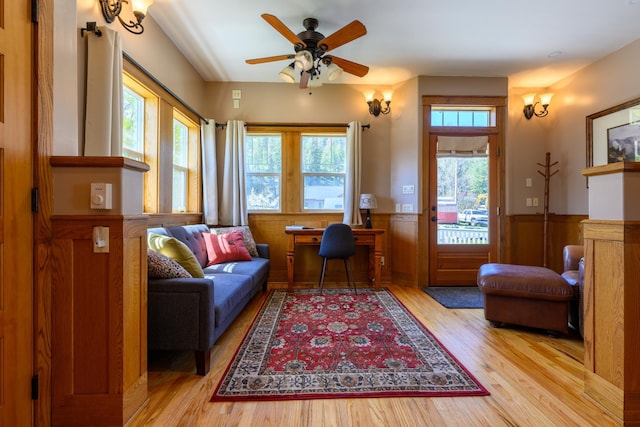 sitting room with wainscoting, ceiling fan, light wood-type flooring, and plenty of natural light