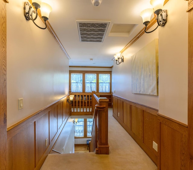 hall featuring an upstairs landing, crown molding, a wainscoted wall, and visible vents