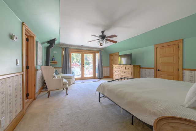 carpeted bedroom with vaulted ceiling, ceiling fan, access to outside, and a wainscoted wall