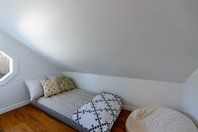 bedroom featuring lofted ceiling, baseboards, and wood finished floors