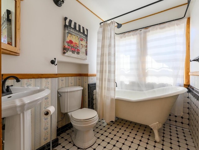 full bath with toilet, radiator heating unit, wainscoting, a sink, and a freestanding tub