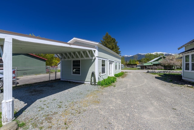 view of side of home with a mountain view, driveway, and fence