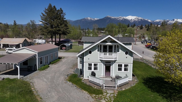 rear view of property with central air condition unit, gravel driveway, a deck with mountain view, and a balcony