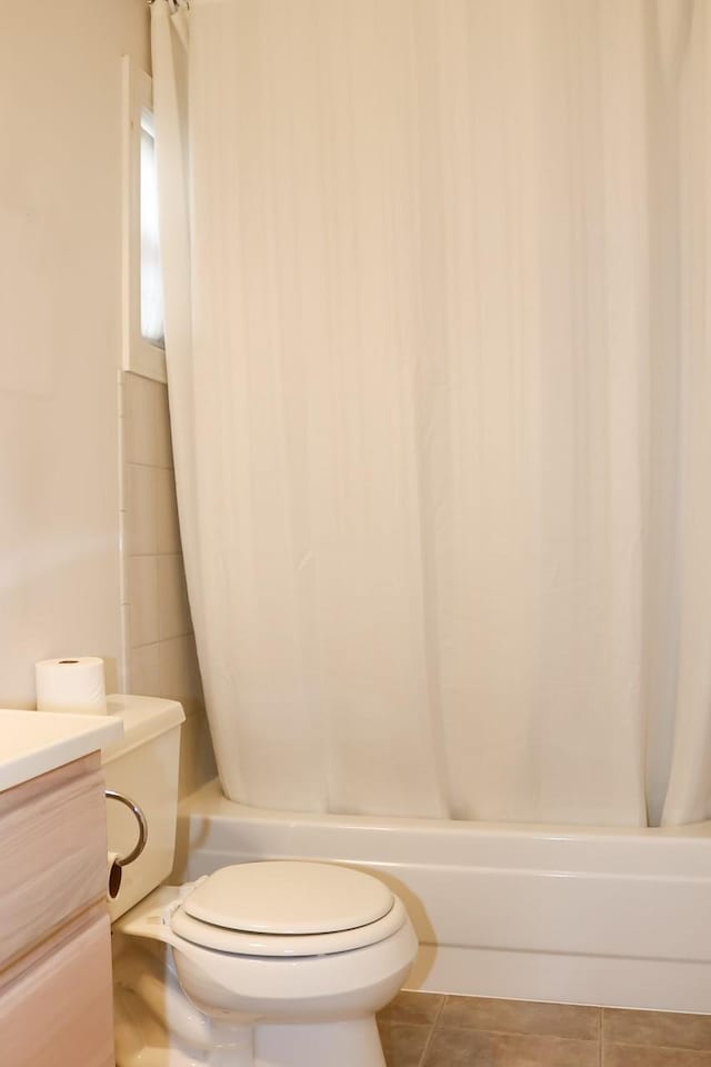 bathroom featuring toilet, tile patterned flooring, vanity, and shower / bathtub combination with curtain